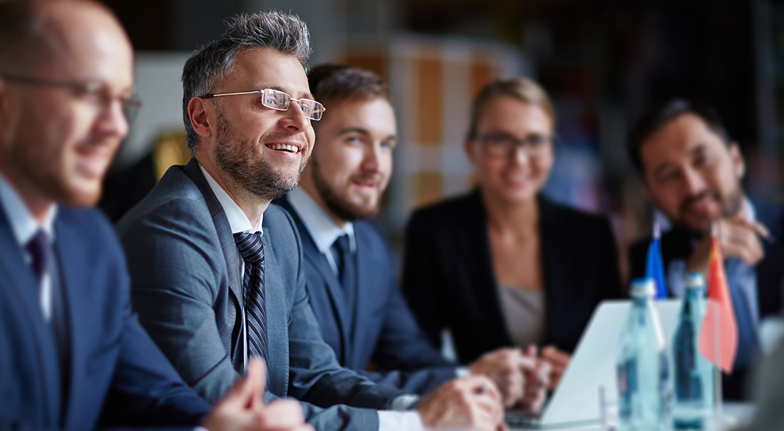 Image of business men in suits sitting around a board table